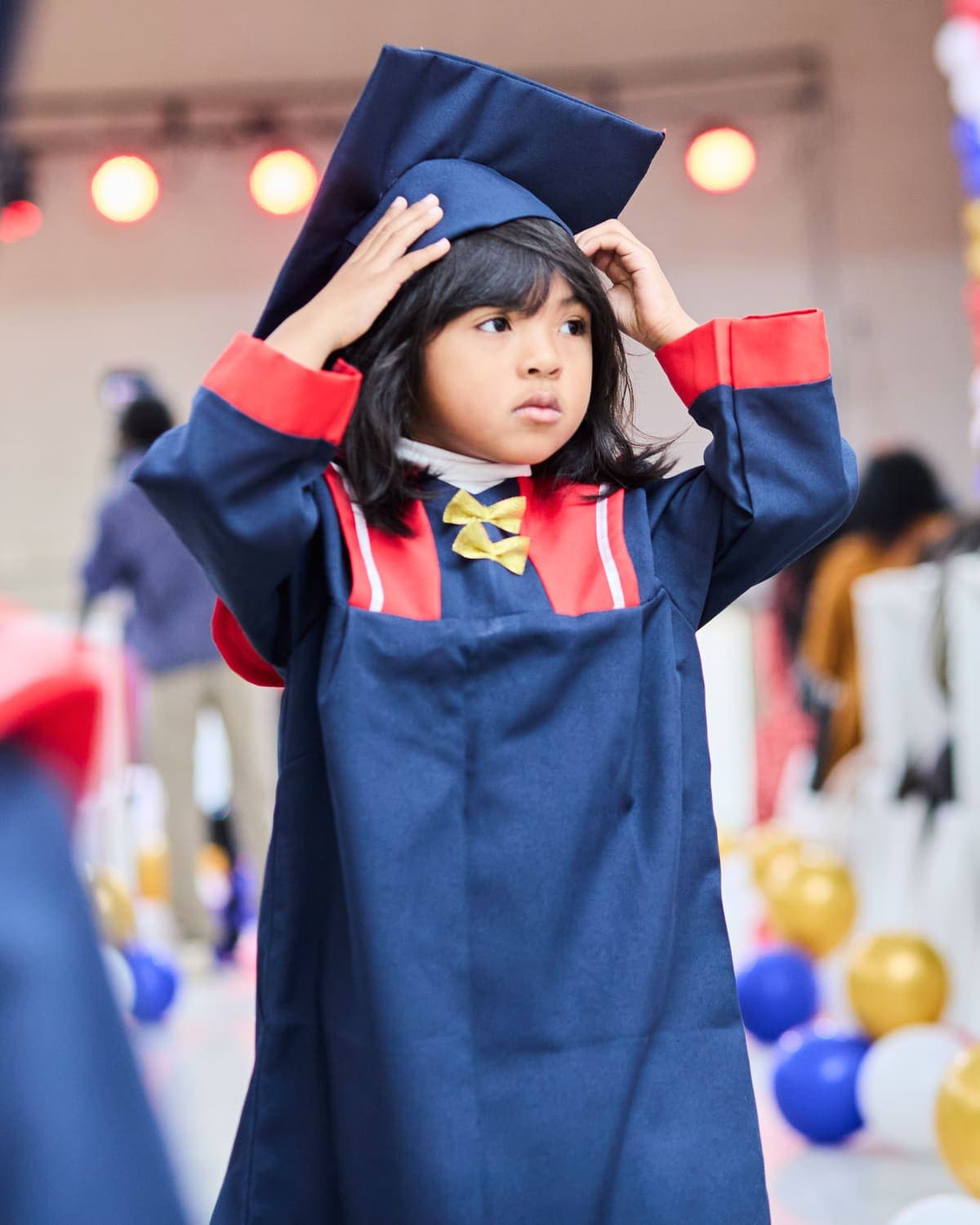 A child in a navy graduation cap and gown at a school ceremony