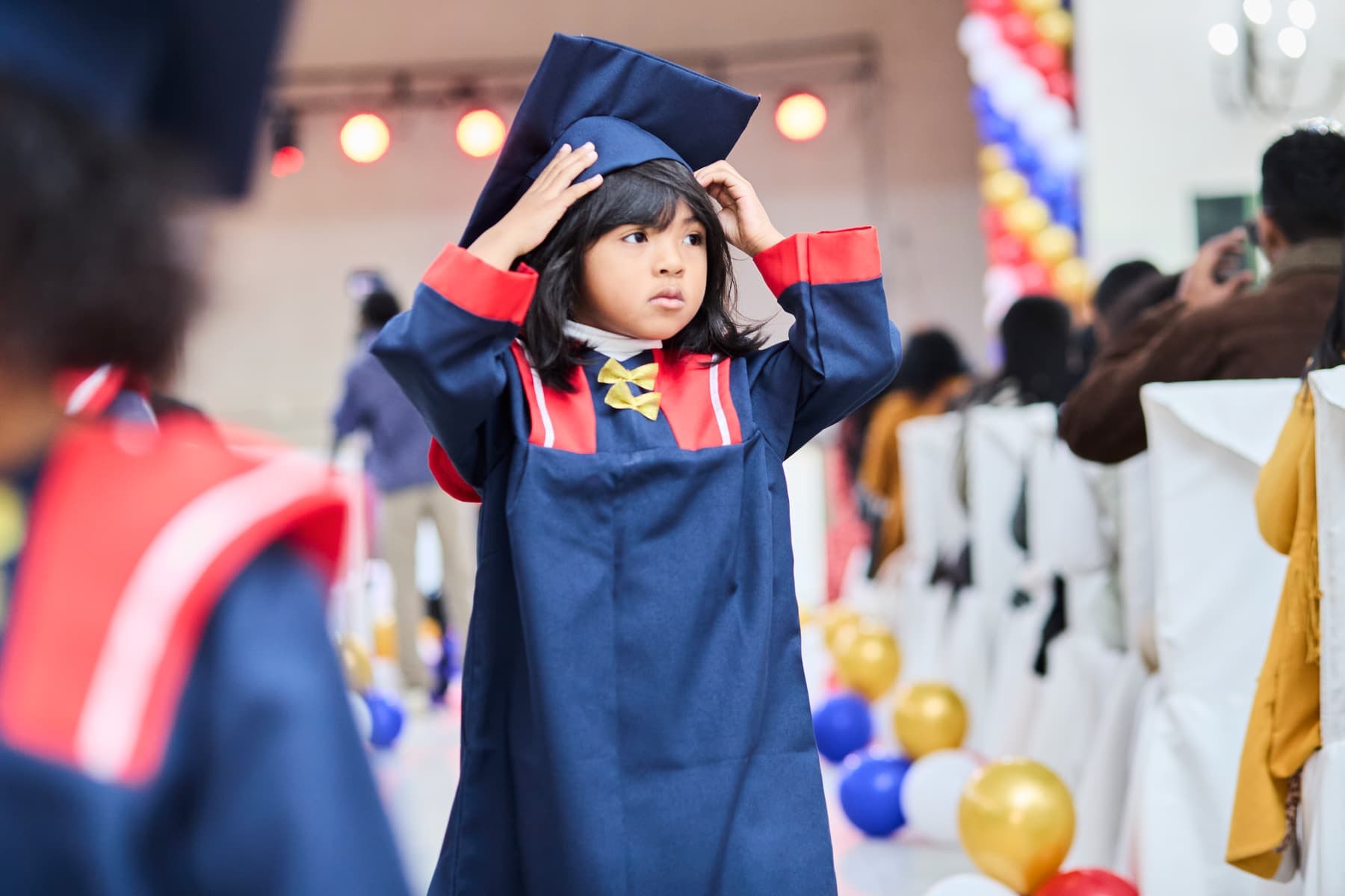 A child in a graduation cap and gown at a school ceremony