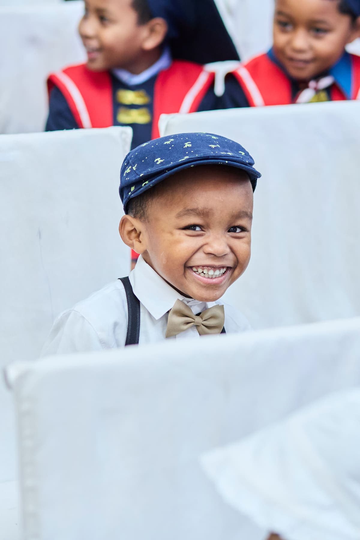 A smiling child in a navy cap and bow tie